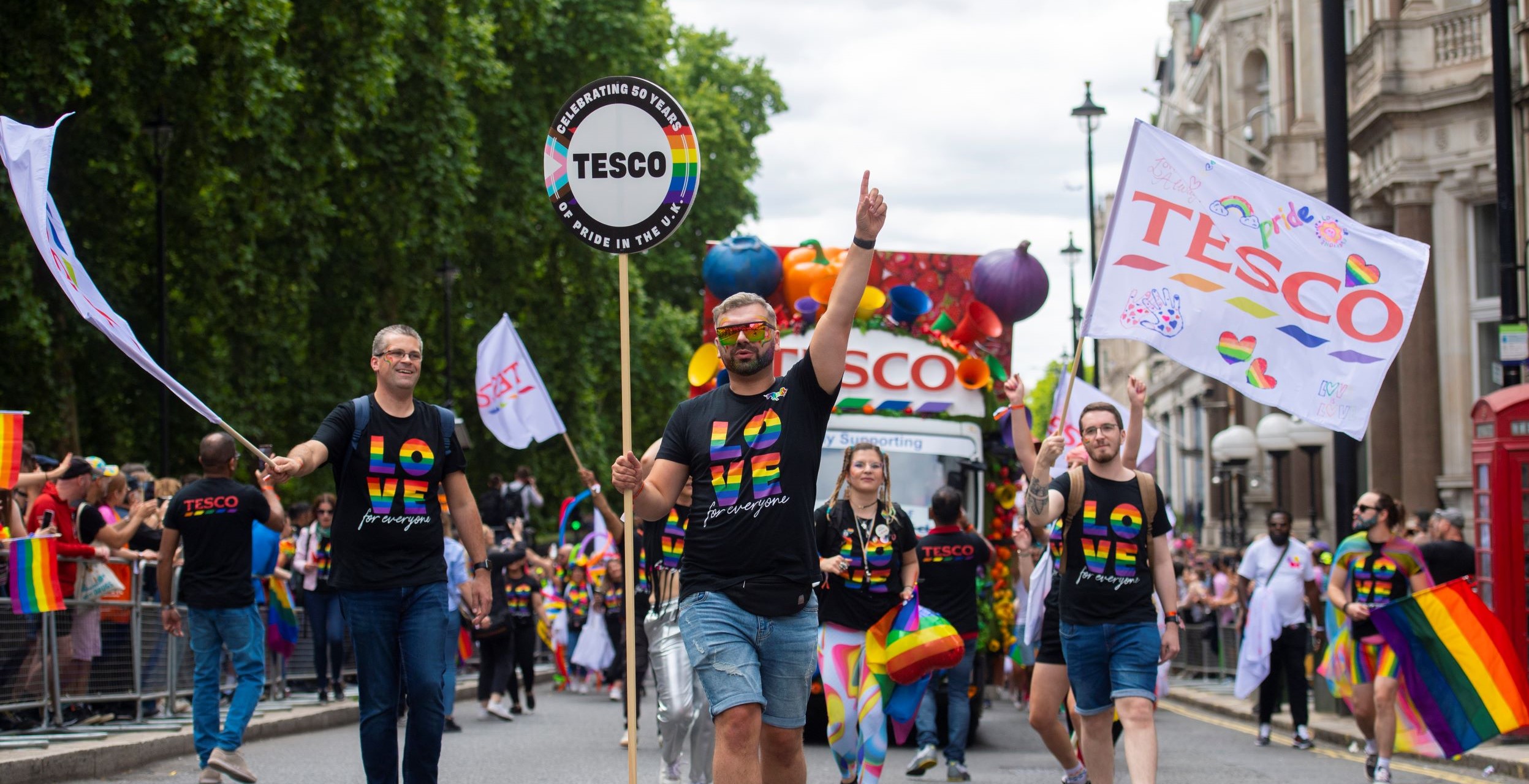 Colleagues walking in front of the Tesco Pride float enjoying themselves